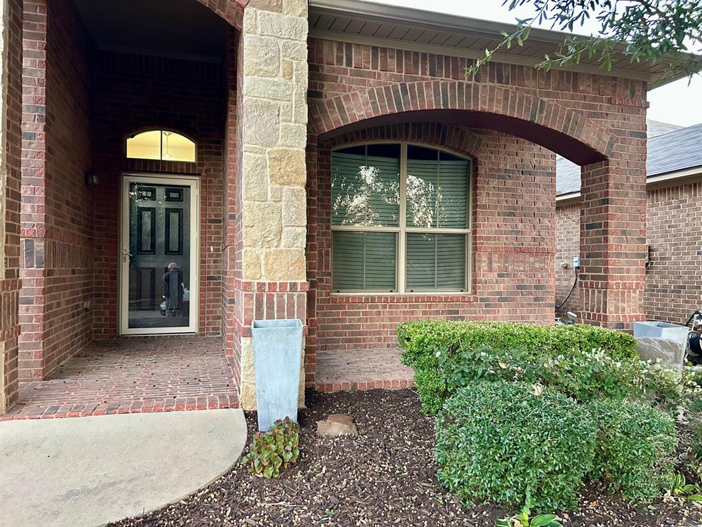 3105 Pecan Tree Drive Denton, TX 76210 - Photo 25 of 25 Doorway to property featuring brick siding and covered porch