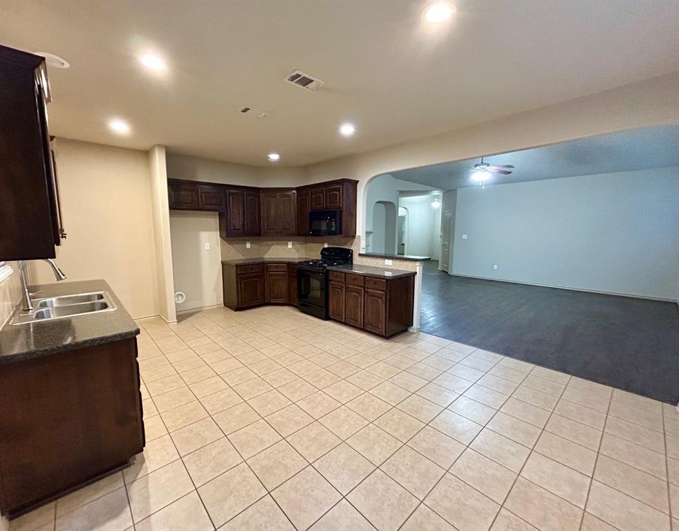 3105 Pecan Tree Drive Denton, TX 76210 - Photo 10 of 25 Kitchen featuring arched walkways, dark brown cabinetry, a ceiling fan, light tile patterned flooring, and black appliances