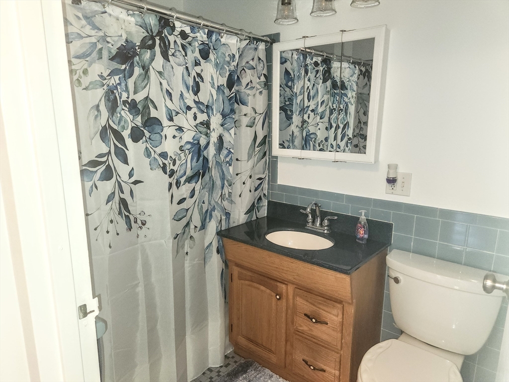 1003 North Main Street, Unit 7 Randolph, MA 02368 - Photo 17 of 31 a bathroom with a granite countertop sink toilet and mirror