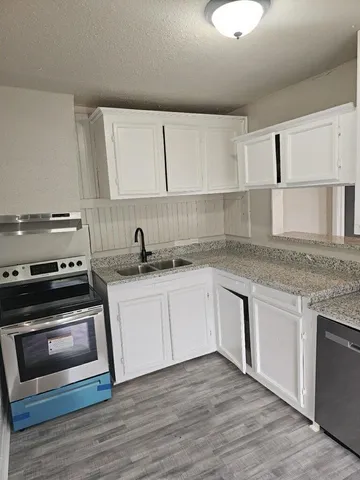 a kitchen with granite countertop a stove a sink and a microwave