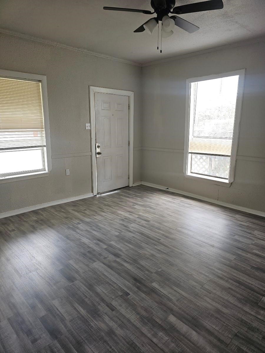 8010 Miley Street Houston, TX 77028 - Photo 3 of 8 an empty room with wooden floor chandelier fan and windows