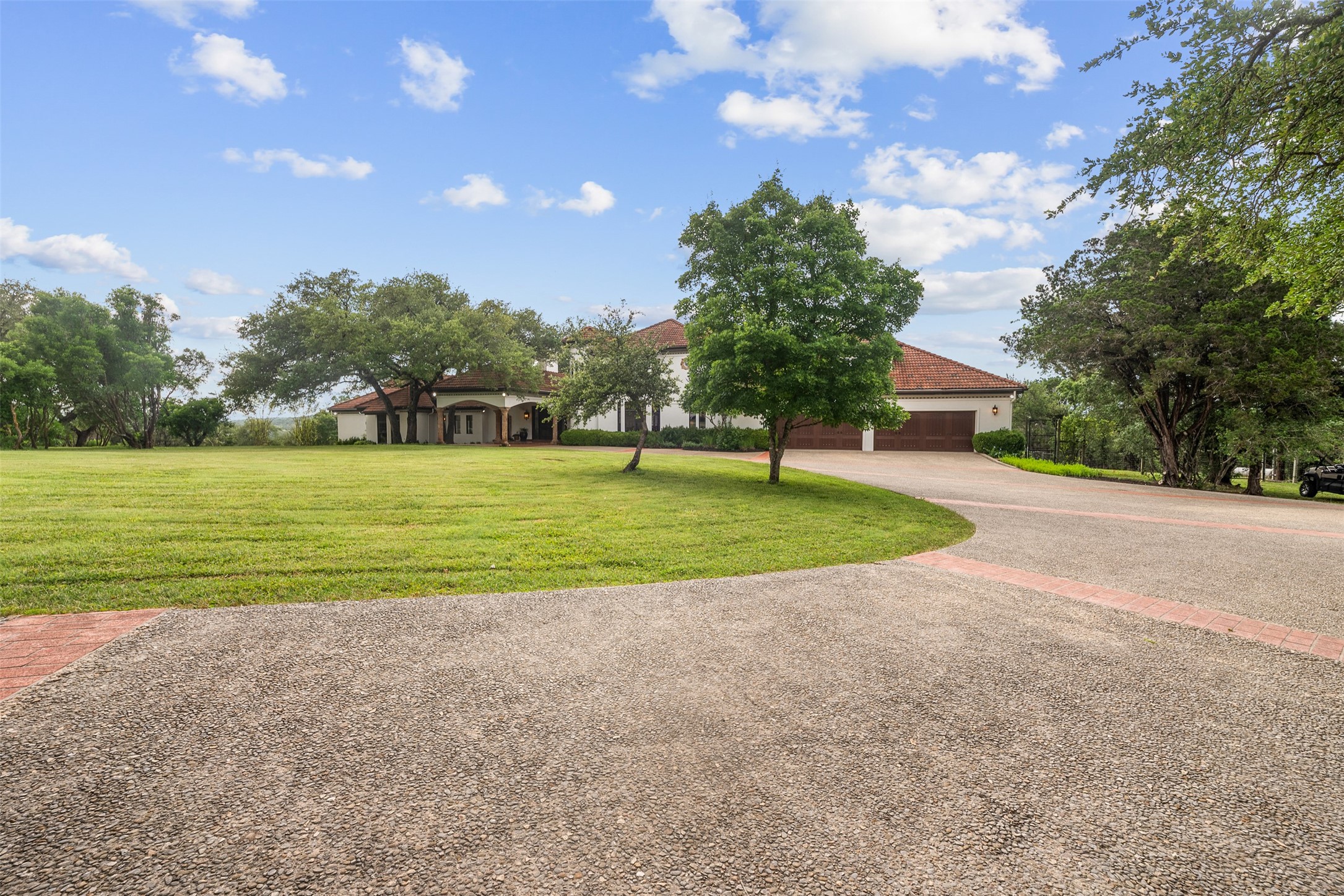 34000 Smithson Valley Road Bulverde, TX 78163 - Photo 2 of 50 A sweeping circular drive welcomes guests to this secluded retreat, offering abundant parking and a grand approach. Mature landscaping and elevated surroundings enhance the property's privacy and prestige.