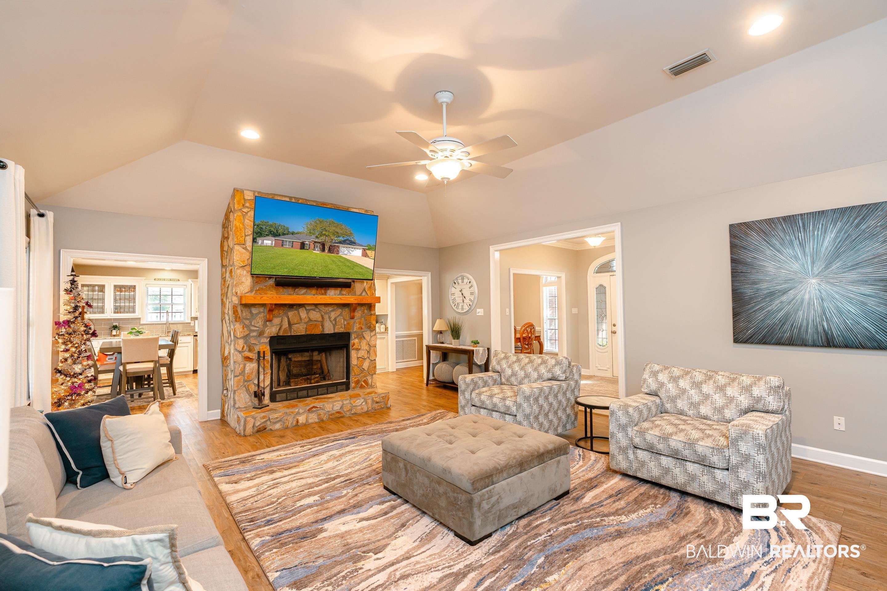9477 Deerfield Drive Irvington, AL 36544 - Photo 4 of 58 Living room featuring a fireplace, ceiling fan, vaulted ceiling, and light wood-type flooring