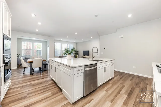 a large white kitchen with wooden floor and a sink