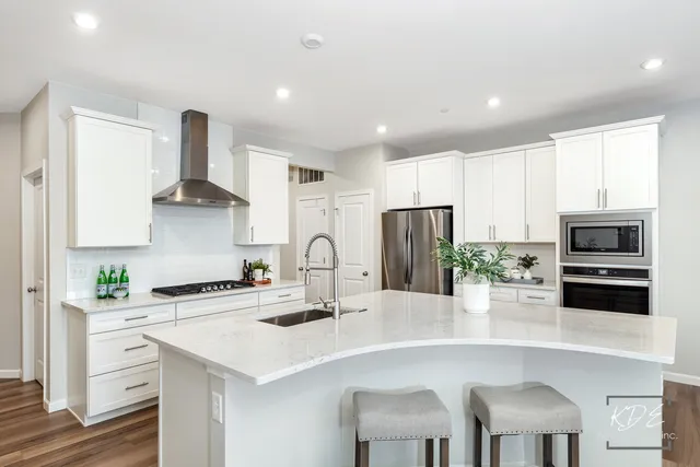 a kitchen with stainless steel appliances a sink a stove a refrigerator cabinets and a dining table