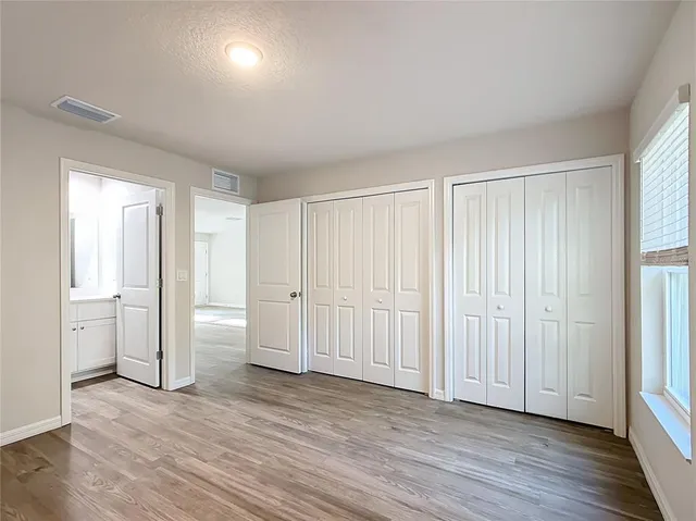 an empty room with wooden floor & windows and closet