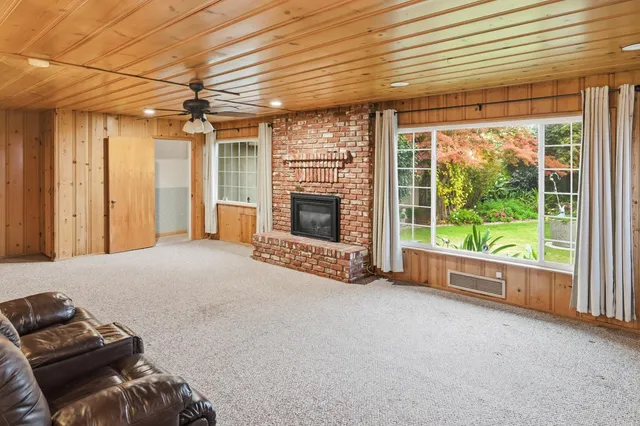 a view of a livingroom with furniture a fireplace and windows
