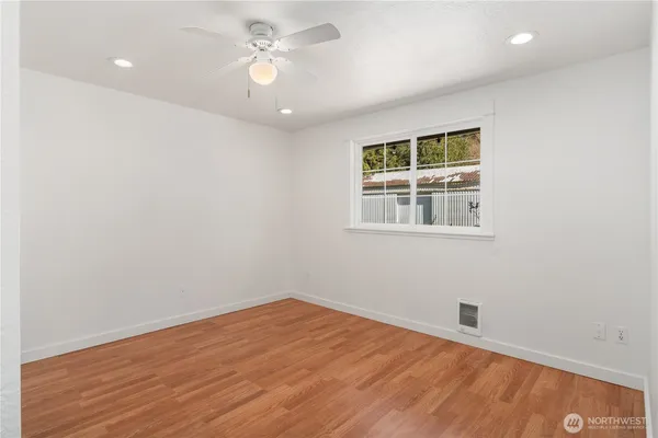 an empty room with a window and ceiling fan