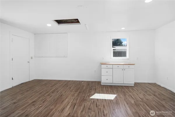 a view of an empty room with wooden floor and windows
