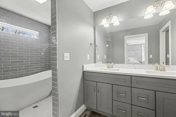 a bathroom with a double vanity sink mirror and bathtub