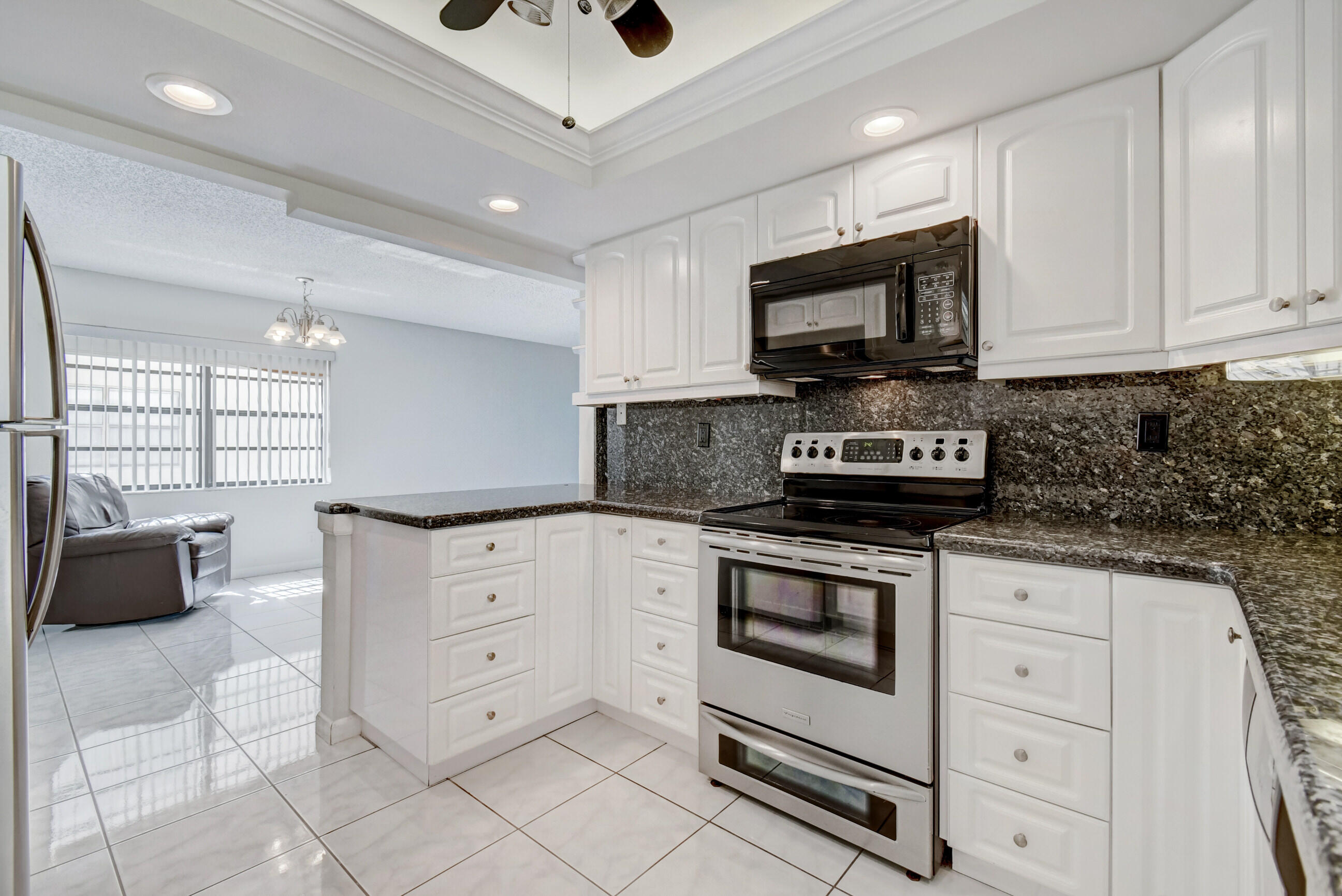 61 Capri B Delray Beach, FL 33484 - Photo 7 of 46 a kitchen with white cabinets stainless steel appliances and a sink