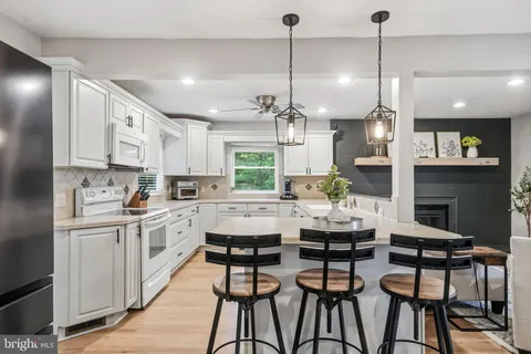 a kitchen with stainless steel appliances kitchen island granite countertop a table chairs and white cabinets