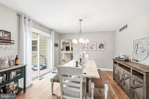 a view of a dining room and livingroom with furniture wooden floor a rug a painting and a chandelier