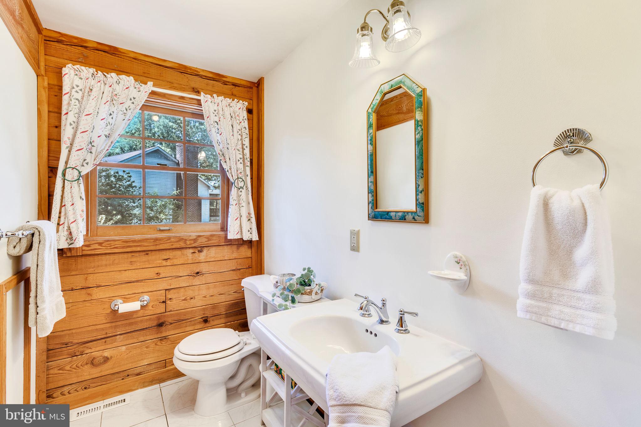 1280 Kelley Neck Road Lancaster, VA 22503 - Photo 27 of 51 a bathroom with a toilet a sink a mirror and a window