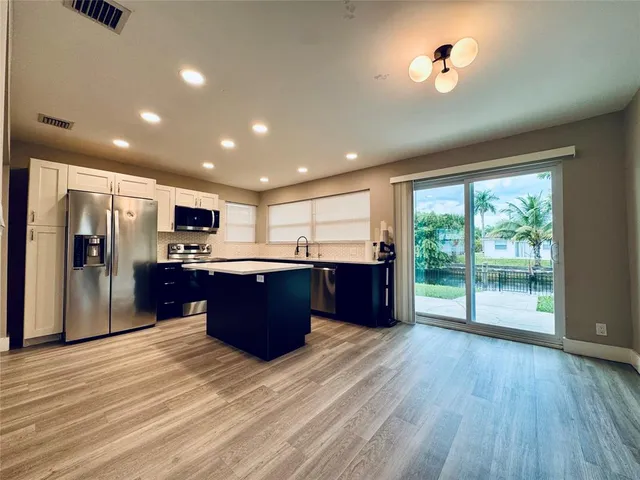 a large kitchen with stainless steel appliances granite countertop a large counter top a sink with wooden cabinets and floors