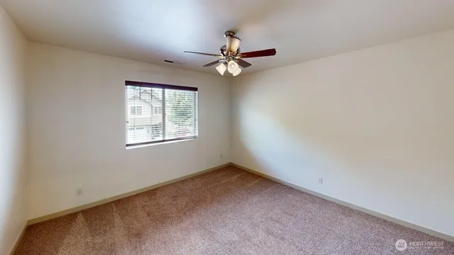 an empty room with a window and a fan
