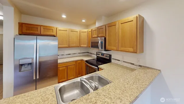a kitchen with stainless steel appliances granite countertop a refrigerator a stove and a sink