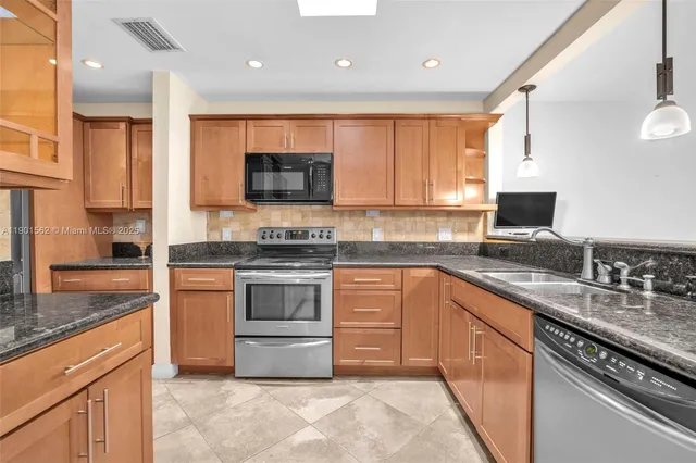 a kitchen with stainless steel appliances granite countertop a sink a stove and a refrigerator