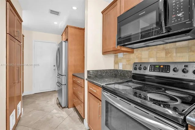 a kitchen with stainless steel appliances granite countertop a stove a sink and a refrigerator