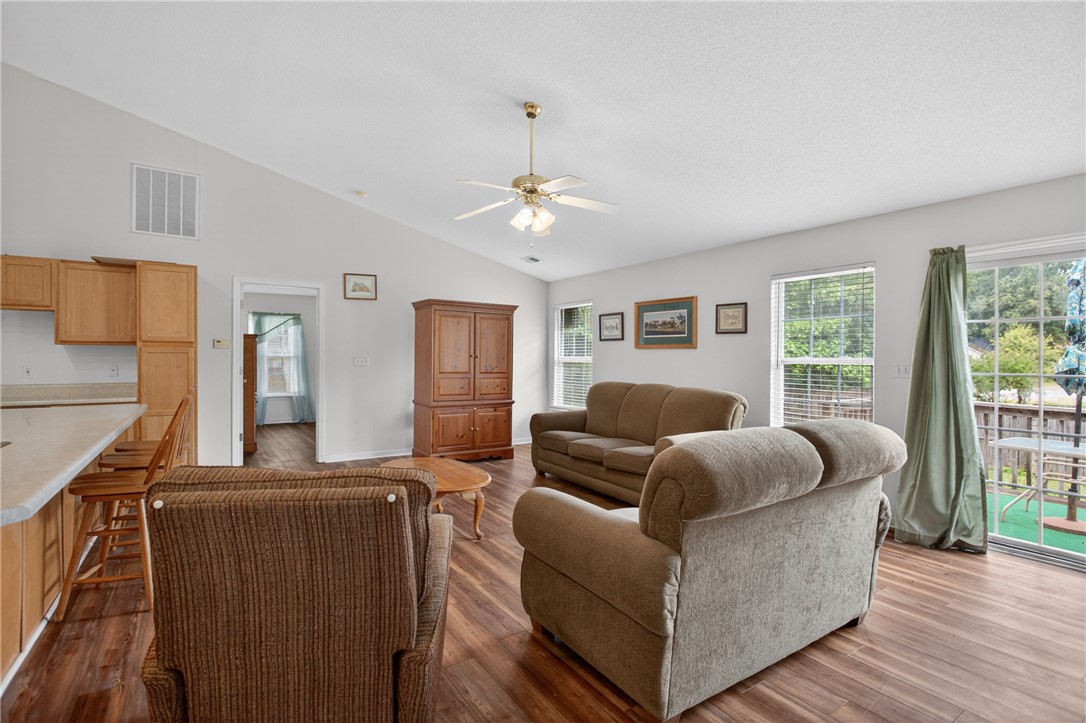 207 Hunters Lane Anderson, SC 29625 - Photo 9 of 46 A well-lit great room features vaulted ceilings and rich wood flooring, connecting seamlessly to a functional kitchen bar.