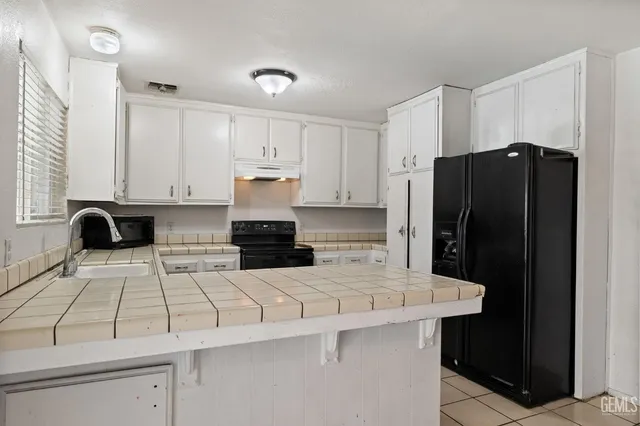 a kitchen with a sink a refrigerator and cabinets