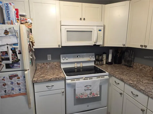 a kitchen with granite countertop a sink stove and cabinets