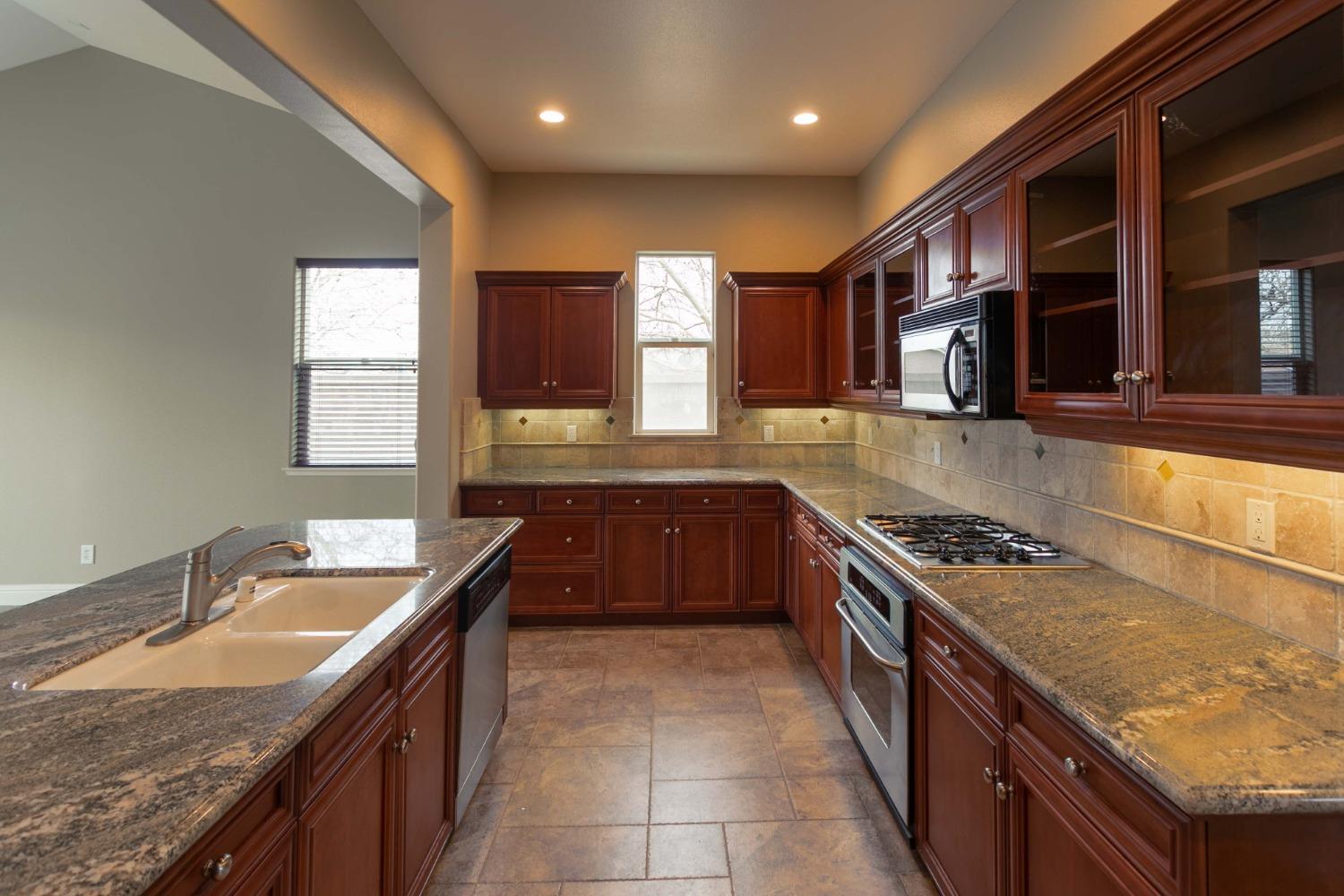 3271 Graybark Avenue Clovis, CA 93619 - Photo 4 of 26 a large kitchen with granite countertop a sink and a stove