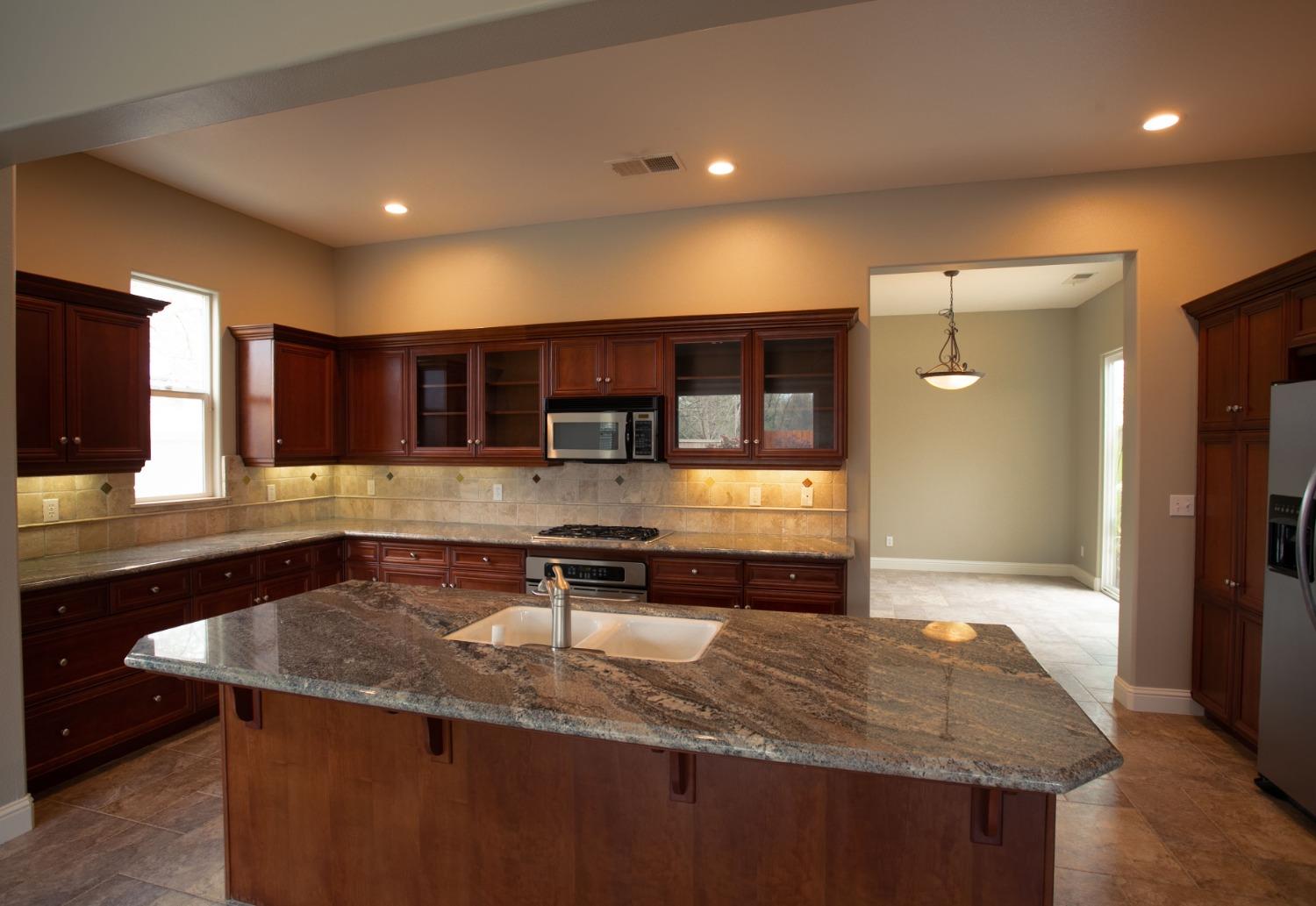3271 Graybark Avenue Clovis, CA 93619 - Photo 5 of 26 a kitchen with stainless steel appliances granite countertop a sink a stove and a refrigerator