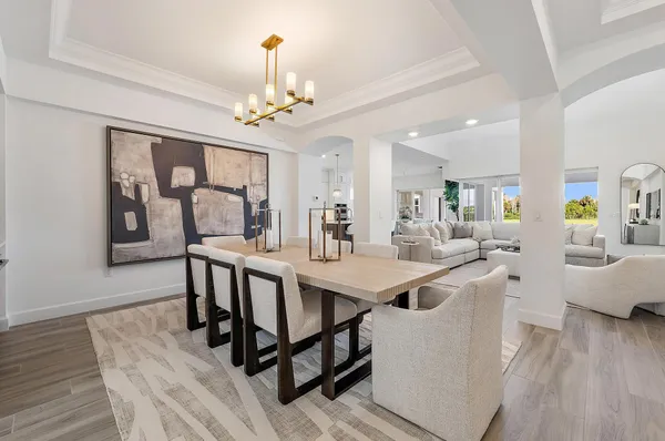 a kitchen with stainless steel appliances kitchen island granite countertop a table chairs stove and white cabinets