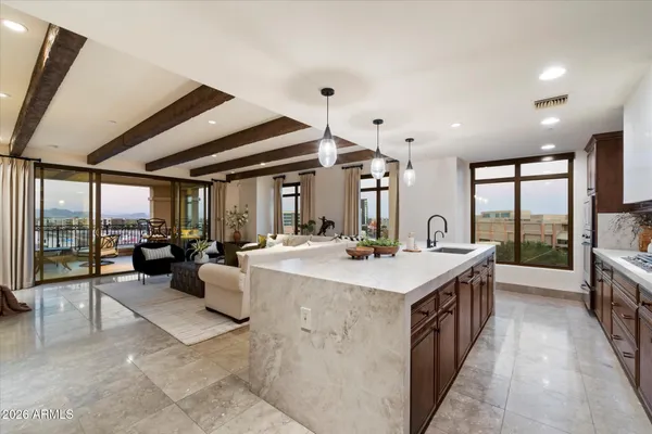 a large kitchen with kitchen island a stove a sink a counter space and a view of living room