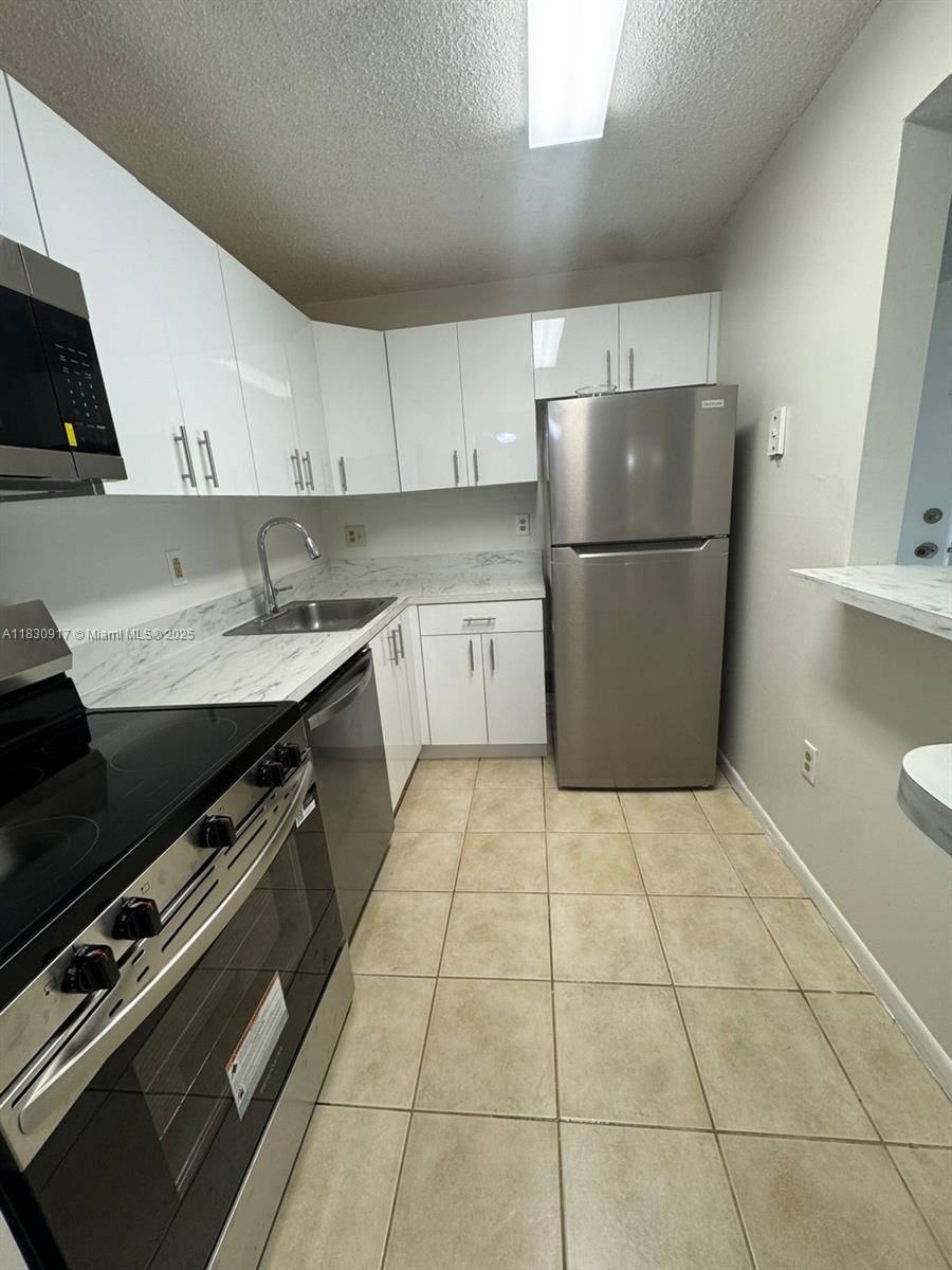 7180 Northwest 179th Street, Unit 109 Hialeah, FL 33015 - Photo 6 of 17 a kitchen with a sink a refrigerator and cabinets