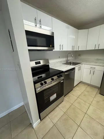 a kitchen with stainless steel appliances a sink dishwasher stove top oven and cabinets