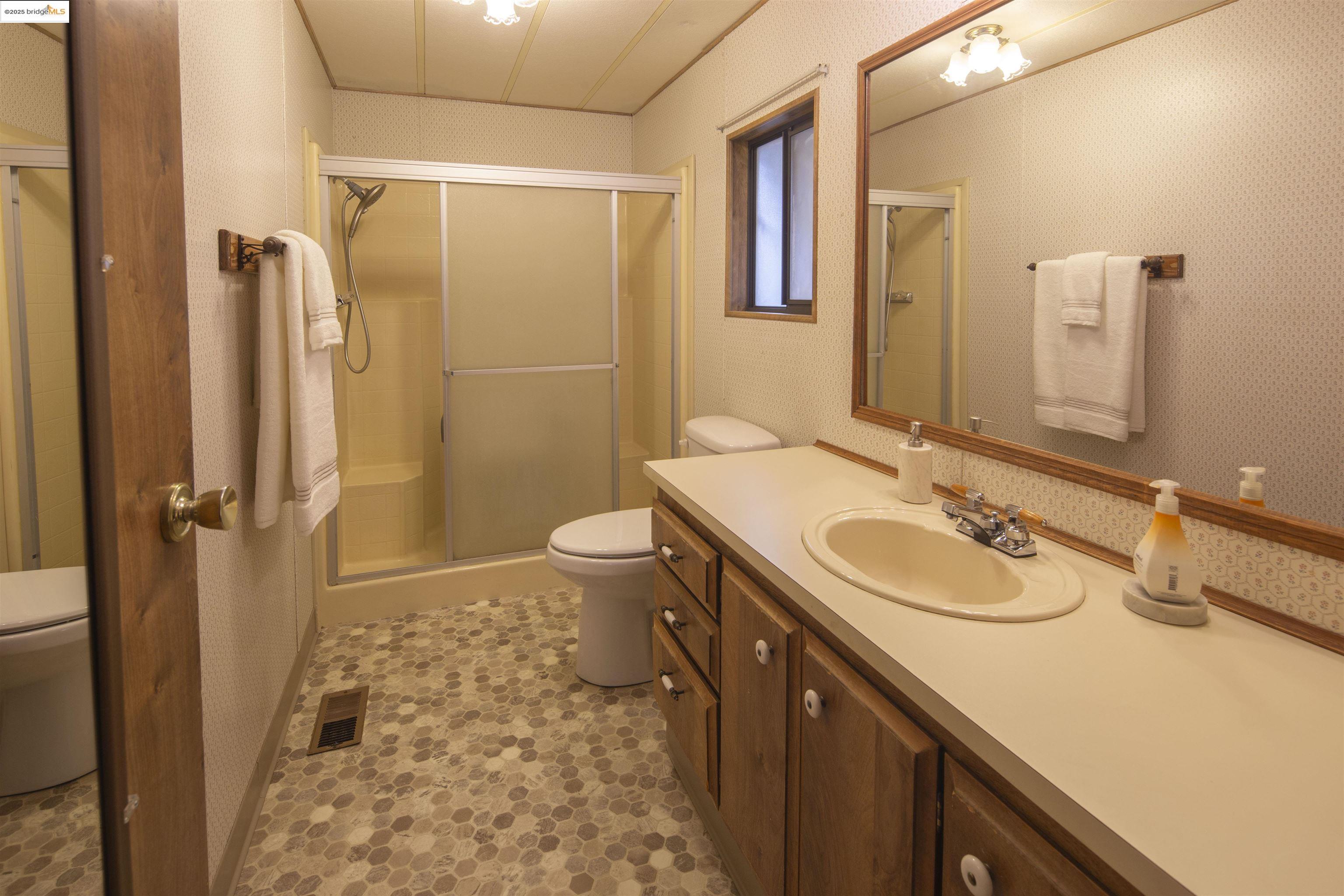 18717 Mill Villa Road, Unit 156 Jamestown, CA 95327 - Photo 22 of 40 Full bathroom with wallpapered walls, vanity, and a shower stall