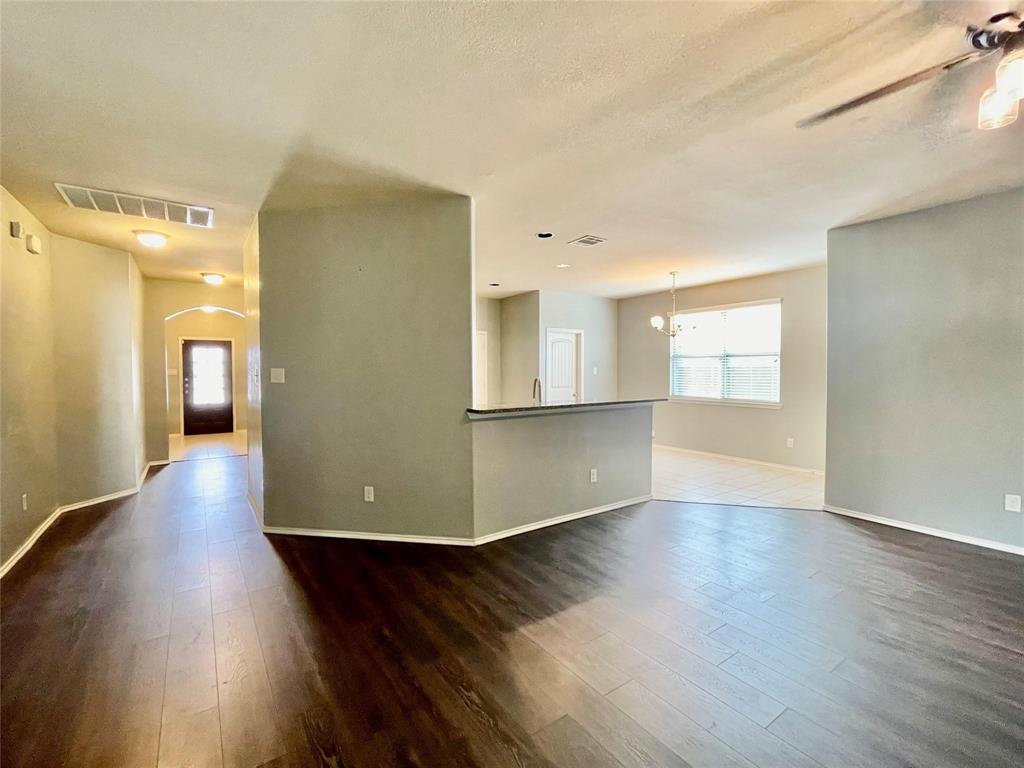1005 Lake Woodland Drive Little Elm, TX 75068 - Photo 10 of 37 Empty room with dark wood-style floors and a chandelier