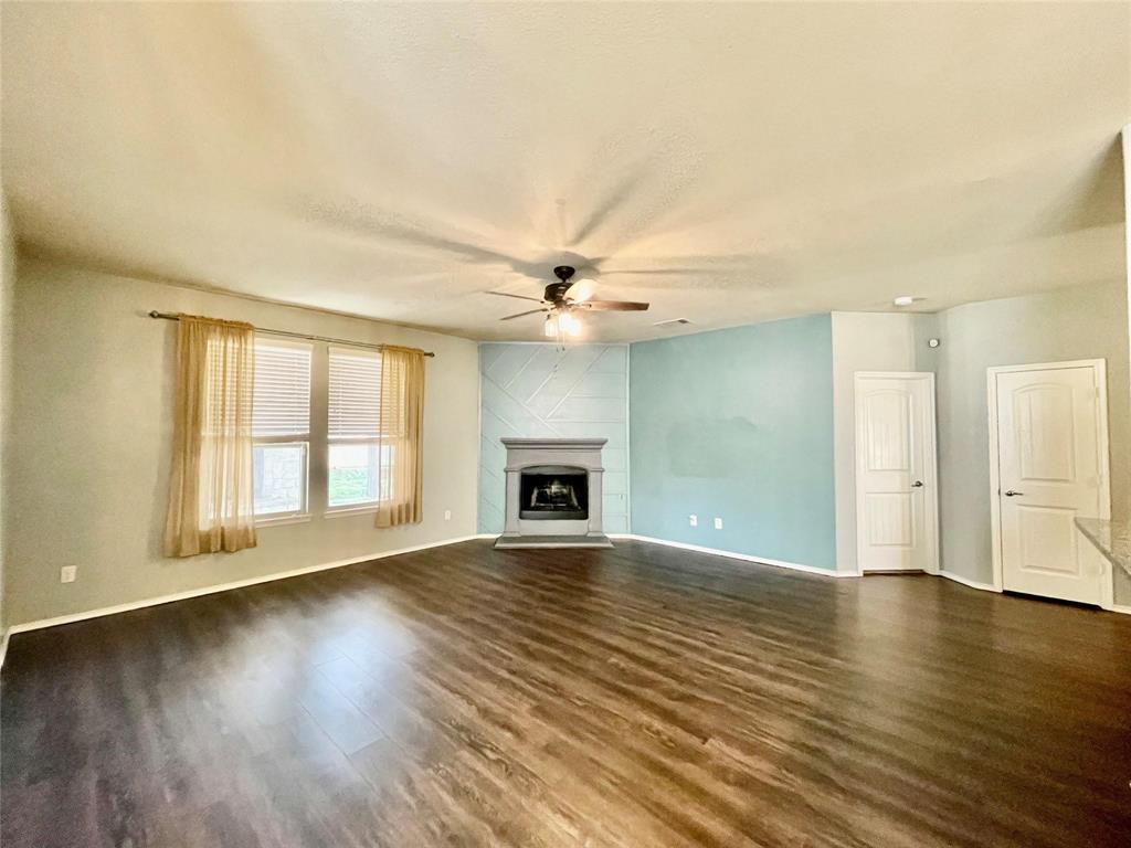 1005 Lake Woodland Drive Little Elm, TX 75068 - Photo 11 of 37 Unfurnished living room with a large fireplace, dark wood-style floors, and ceiling fan