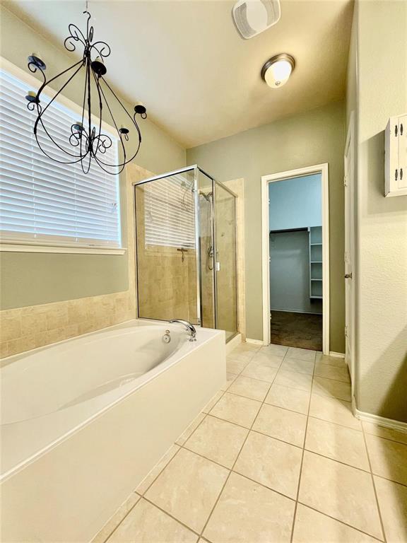 1005 Lake Woodland Drive Little Elm, TX 75068 - Photo 20 of 37 Bathroom featuring a walk in closet, a garden tub, a stall shower, light tile patterned flooring, and a chandelier