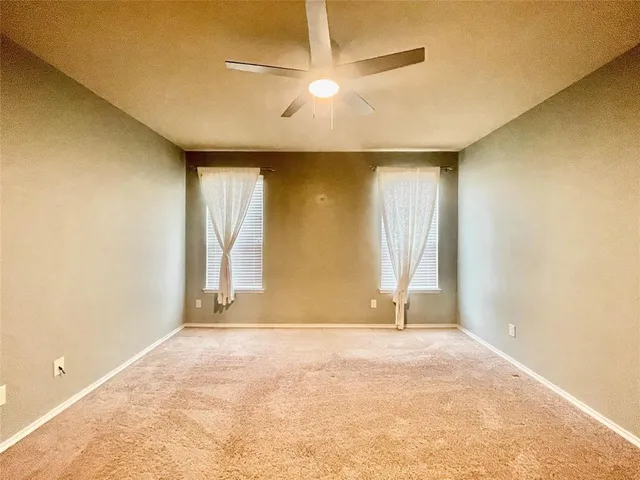 an empty room with a window and a ceiling fan
