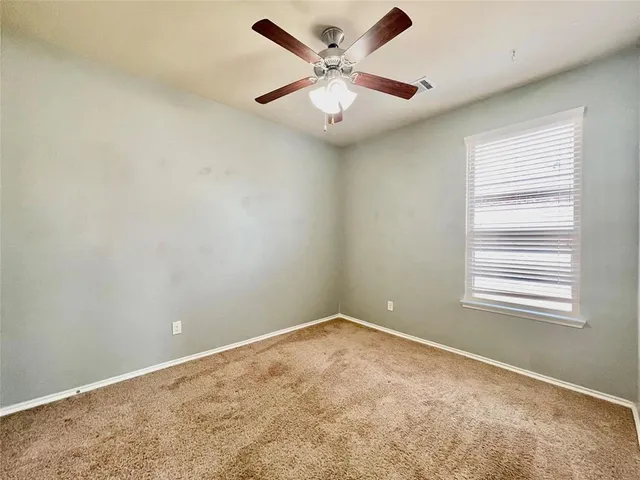 an empty room with a window and a fan