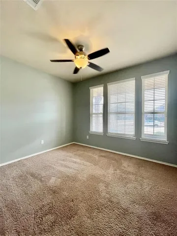 an empty room with chandelier fan and windows