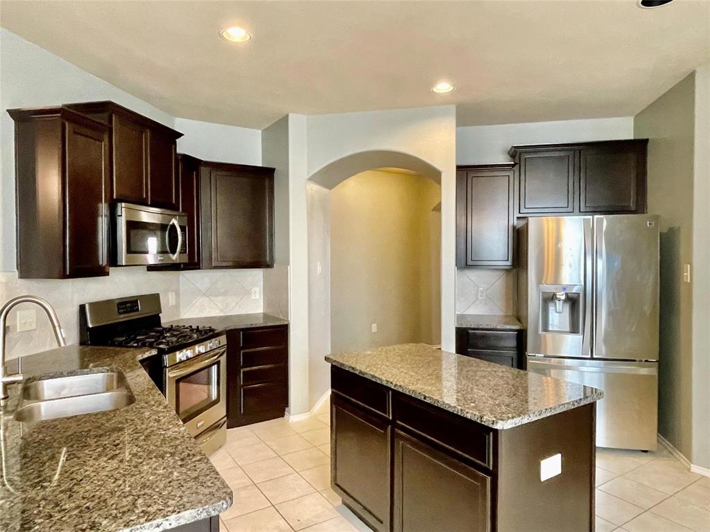 1005 Lake Woodland Drive Little Elm, TX 75068 - Photo 4 of 37 Kitchen featuring arched walkways, appliances with stainless steel finishes, light tile patterned flooring, a kitchen island, and recessed lighting