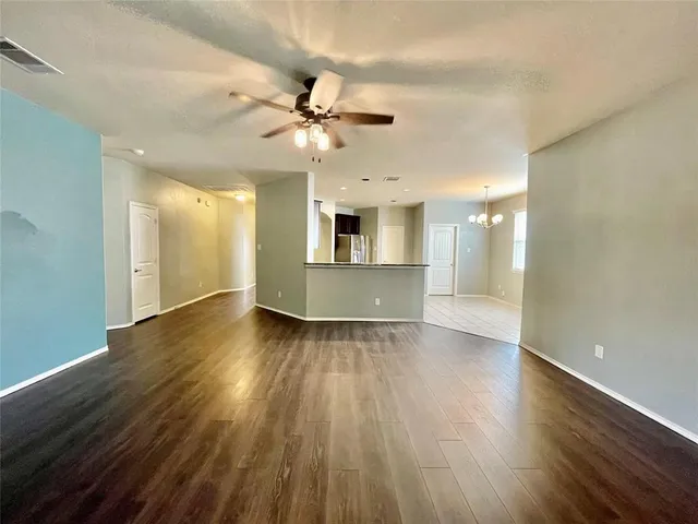 an empty room with wooden floor fireplace and windows