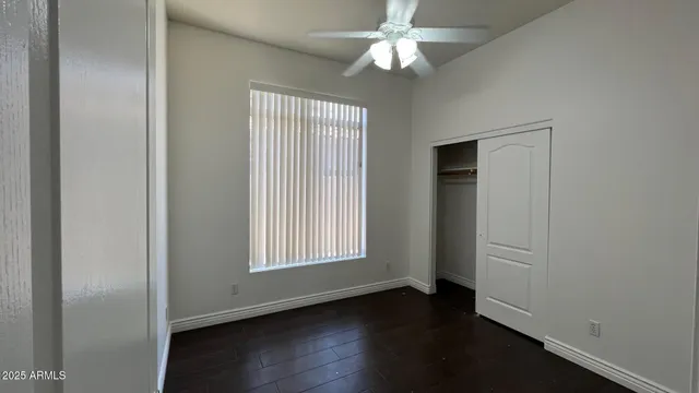 an empty room with wooden floor chandelier fan and windows