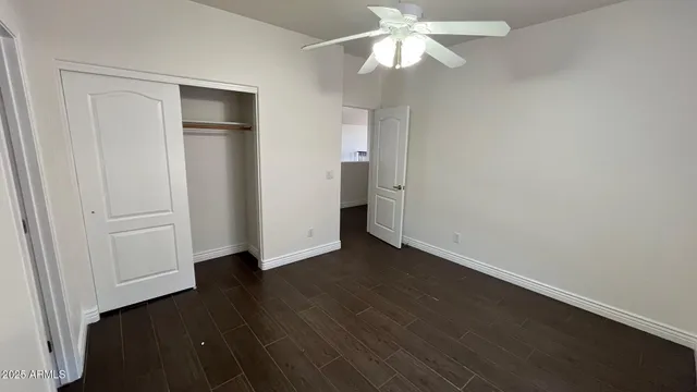 an empty room with wooden floor and ceiling fan