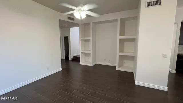 an empty room with wooden floor and ceiling fan