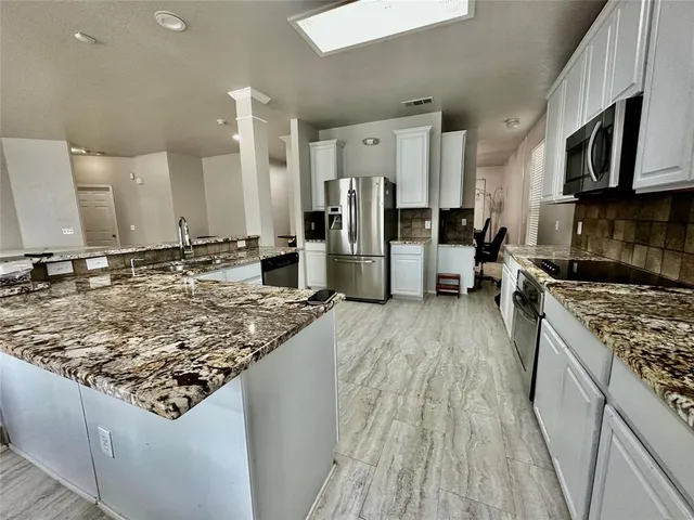 a kitchen with stainless steel appliances granite countertop a lot of counter space and wooden floor