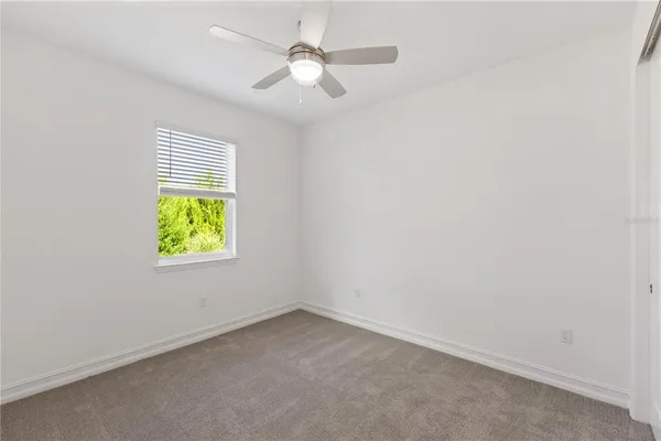 an empty room with a window and a fan