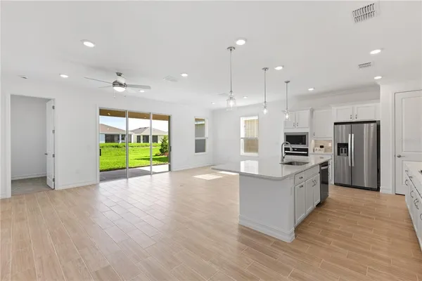 a large kitchen with stainless steel appliances kitchen island a large counter top and wooden floors