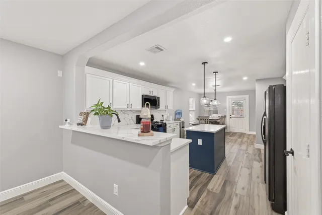 a kitchen with kitchen island white cabinets and refrigerator