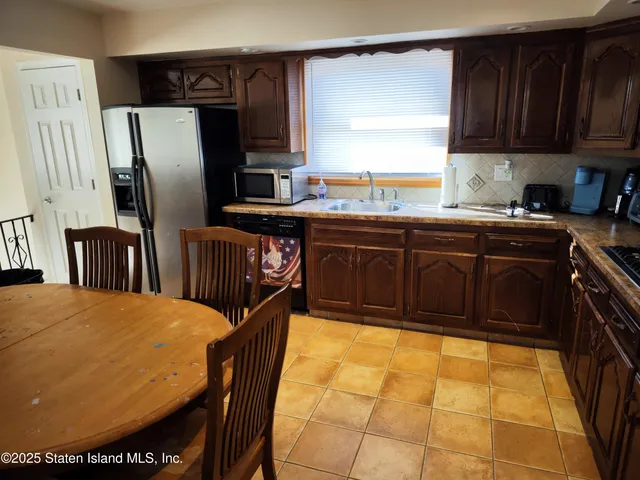 a kitchen with stainless steel appliances granite countertop a refrigerator a sink a stove a dining table and chairs