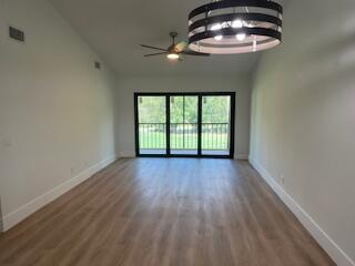 102 Pinecrest Circle, Unit C Jupiter, FL 33458 - Photo 12 of 38 an empty room with a chandelier fan and wooden floor